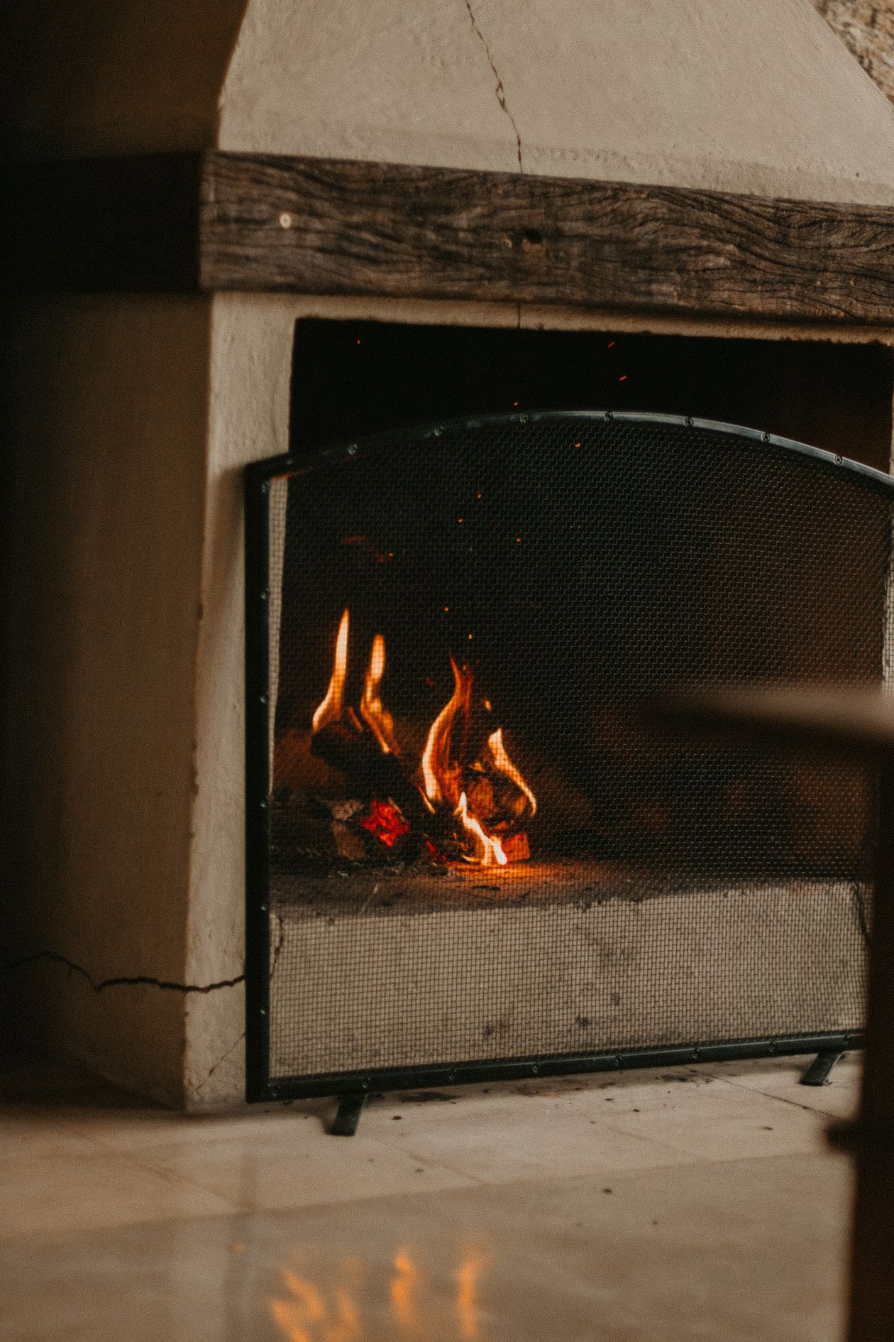 Fireplace with spark-guard screen and lit fire in a Christchurch living room