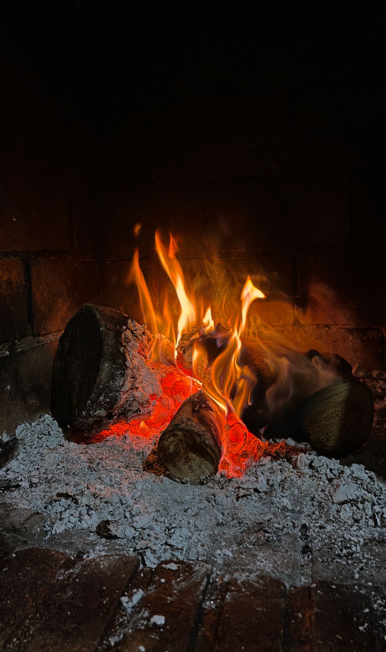 Glowing embers and ash inside a firebox showing why regular chimney cleaning matters