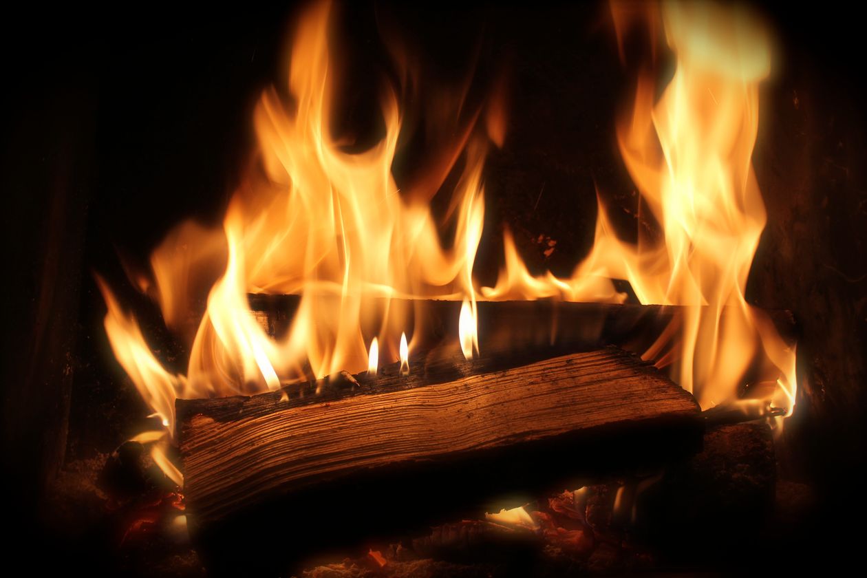 Close-up of a burning log inside a fireplace firebox — professional chimney cleaning in Christchurch